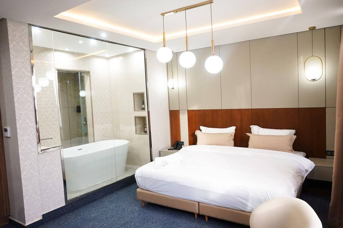 Habitació d'hotel moderna amb un llit gran, dutxa integrada i tocador amb mirall.