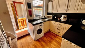 A compact kitchen with a washing machine, a microwave, and a coffee maker. - Gorgeous Cottage in Stoke-on-Trent's "village in the city" - Penkhull (Stoke-on-Trent)