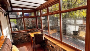 A cozy room with a stone wall, wooden bench, and a table with chairs. - Gorgeous Cottage in Stoke-on-Trent's "village in the city" - Penkhull (Stoke-on-Trent)