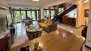 A spacious living area with a large wooden coffee table, a sofa, and a staircase leading to an upper level. - Pipa Blue (Tibau do Sul)