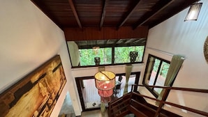 A staircase with a wooden railing, a hanging light fixture, and a view of greenery outside. - Pipa Blue (Tibau do Sul)