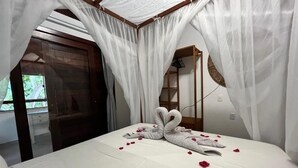 A bedroom with a canopy bed, white linens, and a heart-shaped towel arrangement. - Pipa Blue (Tibau do Sul)