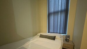 A small, neatly made bed with a single pillow and a bedside table with a lamp. - City Chic Apartment in Leeds (Leeds)