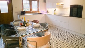 A modern kitchen with a glass dining table, white cabinets, and a checkered floor. - Casa Amor - Aviemore (Aviemore)