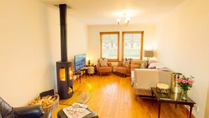 A cozy living room with a wood-burning stove, comfortable seating, a television, and a fireplace. - Casa Amor - Aviemore (Aviemore)