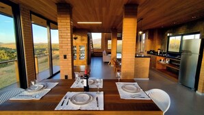 A dining area with a wooden table set for four, large windows, and a view of the countryside. - Ibitipoca Castle (Conceição da Ibitipoca)
