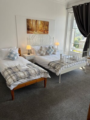 A bedroom with two beds, a painting on the wall, and a window with curtains. - Edinburgh Travel Guest House (Edinburgh)