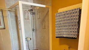 A bathroom with a shower, toilet, and a patterned towel hanging on the wall. - Edinburgh Travel Guest House (Edinburgh)