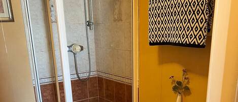 Un baño con ducha, inodoro y una toalla estampada colgada en la pared.