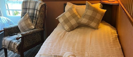 Een hotelkamer met een bed, een stoel, een lamp en een raam.