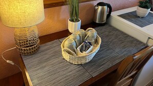 A neatly arranged table with a woven basket containing tea cups, a kettle, and snacks. - Edinburgh Travel Guest House (Edinburgh)
