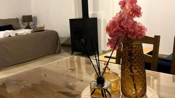 A wooden dining table with a vase of pink flowers and a glass candle holder.