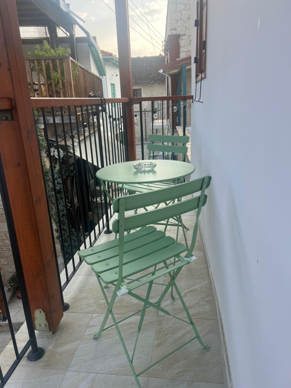 A small outdoor patio with a round table and two green chairs.