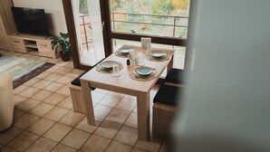 A dining area with a table set for four, a television, and a potted plant.