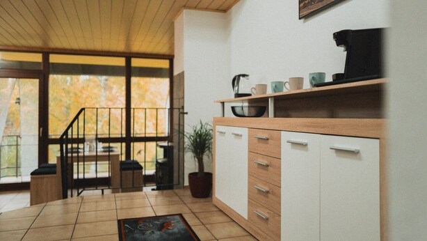 A modern kitchen with a wooden countertop, white cabinets, and a coffee machine.