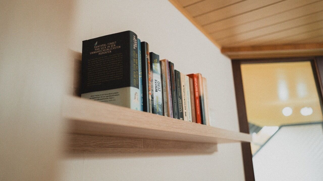 Ein Bücherregal mit Büchern an einer Wand.