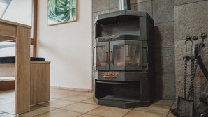 A corner room with a stone wall, a fireplace, and a wooden table.