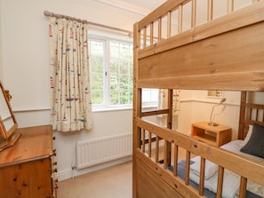 A child's bunk bed with a wooden frame and a window with curtains. - 4 St Elmo Court DO NOT USE (Salcombe)