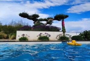 A swimming pool with a unique tree-shaped planter and a yellow float. - La Villa Gracieuse (Grâces)