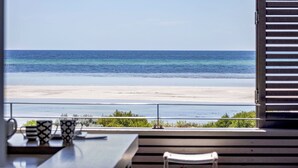 Vista da un balcone su una spiaggia, con un tavolo e delle sedie.