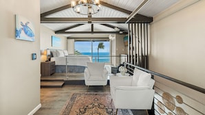 Een ruime woonkamer met een groot raam met uitzicht op de oceaan, een gezellige zithoek met vloerkleed, en een trap met een panoramisch uitzicht.