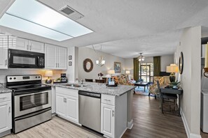 A modern kitchen with a central island, stainless steel appliances, and a dining area with a chandelier. - 2 bedroom, 2 bathroom updated condo with private patio. Centrally located in Augusta, GA (Augusta)