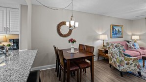 A dining area with a chandelier, a round table with chairs, a floral armchair, and a painting on the wall. - 2 bedroom, 2 bathroom updated condo with private patio. Centrally located in Augusta, GA (Augusta)