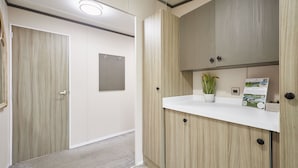 A modern bathroom with wooden cabinetry, a white countertop, and a potted plant. - Host & Stay | Happy Day's Lodge (Pocklington)
