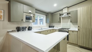 A modern kitchen with a white countertop, stainless steel appliances, and light wood cabinetry. - Host & Stay | Happy Day's Lodge (Pocklington)