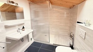 Een moderne badkamer met douche, toilet en wastafel.