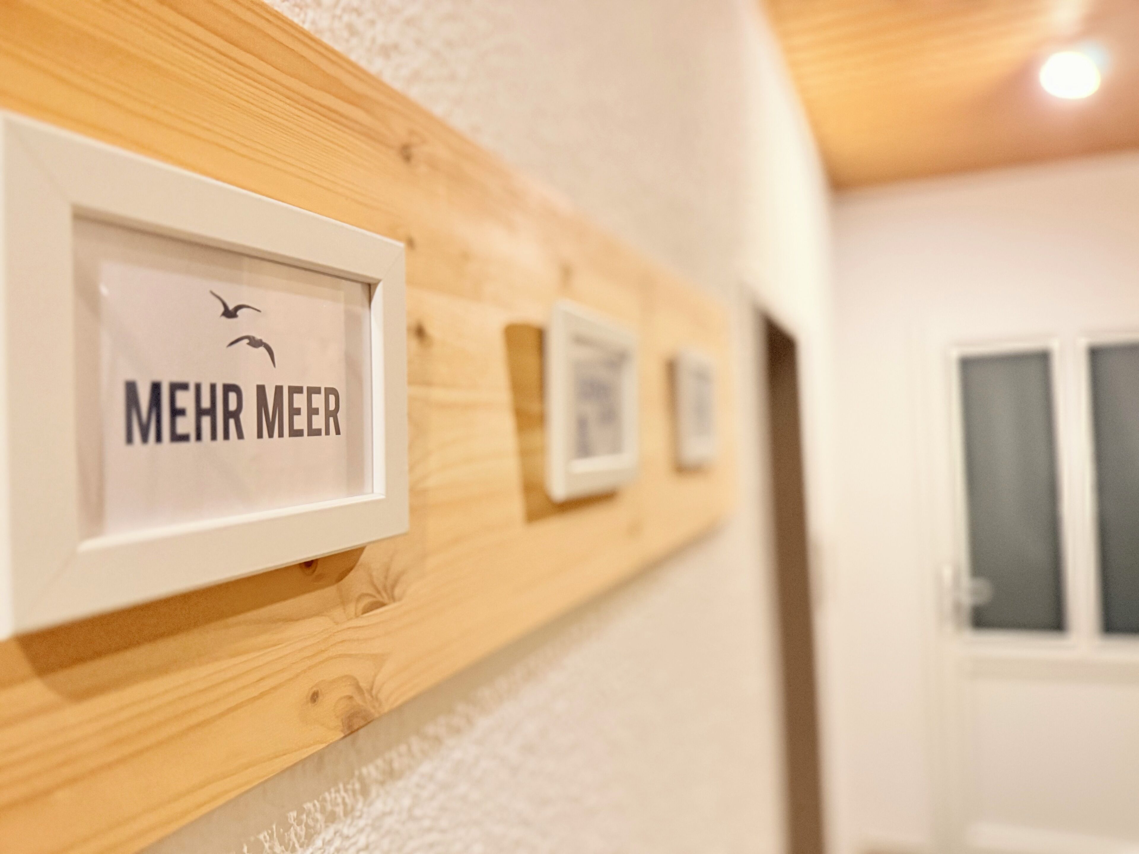 Un corridoio con cartelli incorniciati su un muro di legno, ognuno con la scritta "MEHR MEER".