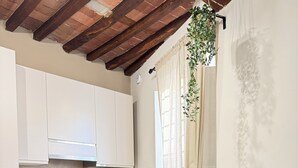 Une cuisine moderne avec des armoires blanches, un plan de travail en bois et une cuisinière à gaz intégrée. On y trouve un petit îlot central avec un bol de pop-corn et deux bouteilles d’eau.