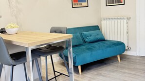 Un espace de vie moderne comprenant une table à manger, des chaises, un canapé de couleur turquoise et deux œuvres d’art abstraites accrochées au mur.