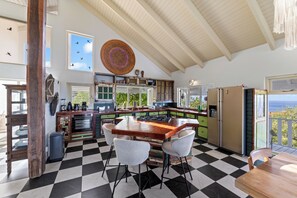 Une cuisine avec un sol à carreaux, un plafond en bois et une vue sur la mer.