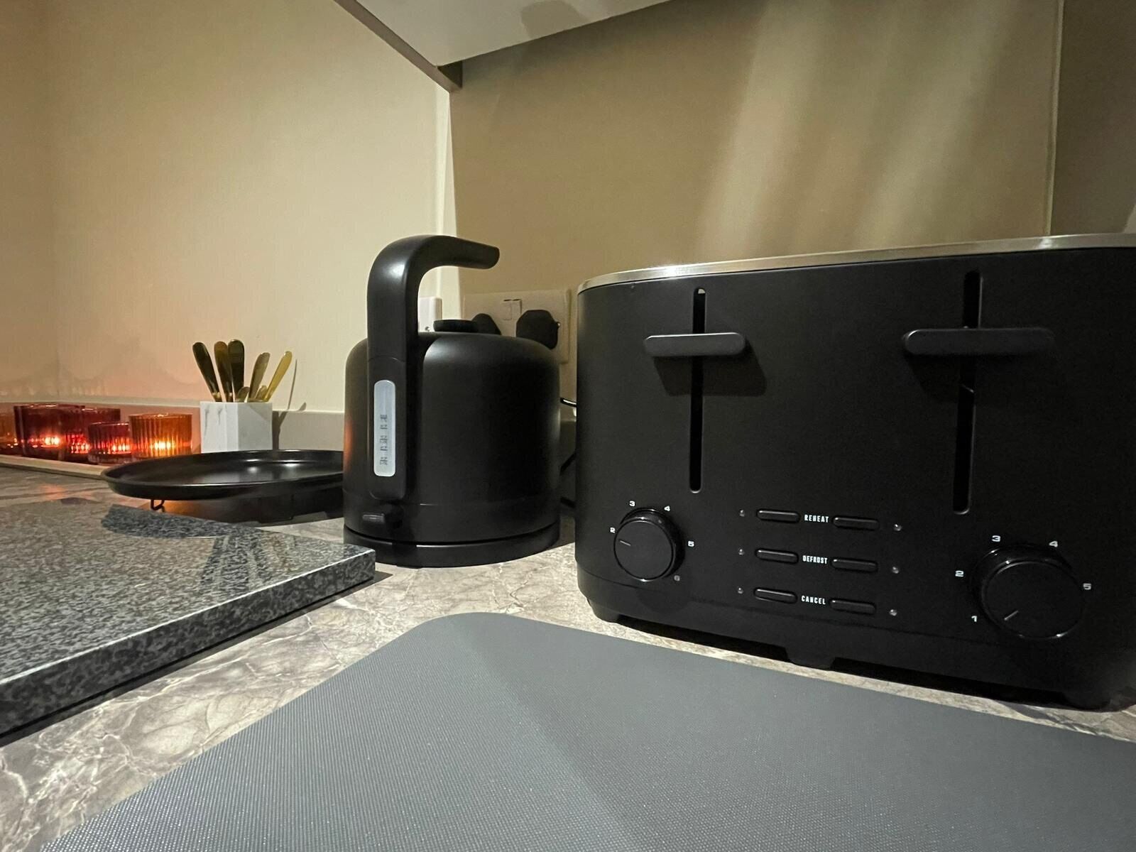 Cozinha com torradeira, chaleira e bandeja com utensílios.