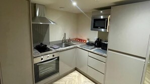 A compact kitchen with a built-in oven, microwave, and stainless steel sink. - Chic Apartment on The Headrow, Leeds (Leeds)
