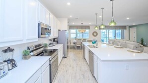 Une cuisine moderne avec des meubles blancs, des appareils en acier inoxydable et un îlot central.