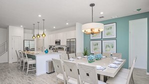 Une cuisine moderne avec des meubles blancs, des appareils en acier inoxydable et un îlot central.