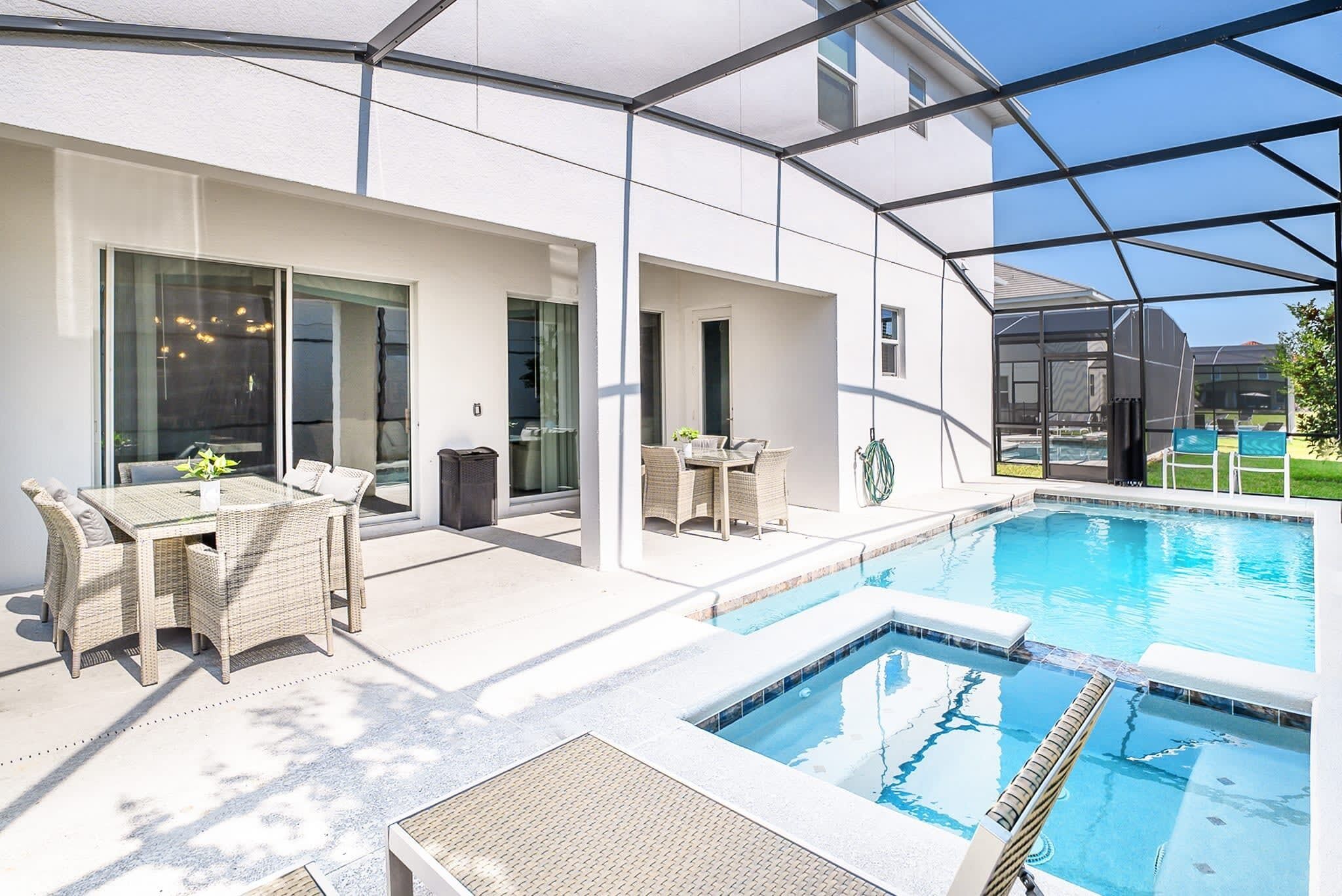 Private screened-in back patio with swimming pool and spill-over hot tub