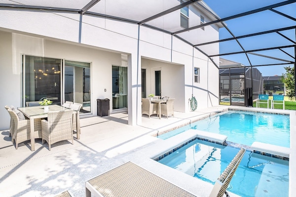 Private screened-in back patio with swimming pool and spill-over hot tub