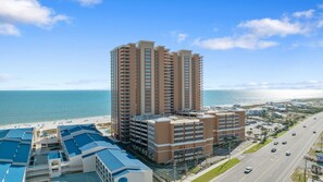 A high-rise hotel with multiple floors, a swimming pool, and a view of the beach and ocean. - Beachfront 3BR, Lazy River/Slide, New to Rentals! (Orange Beach)