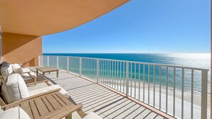 Ein Balkon mit Holzmöbeln, einem weißen Geländer und Blick auf den Ozean.
