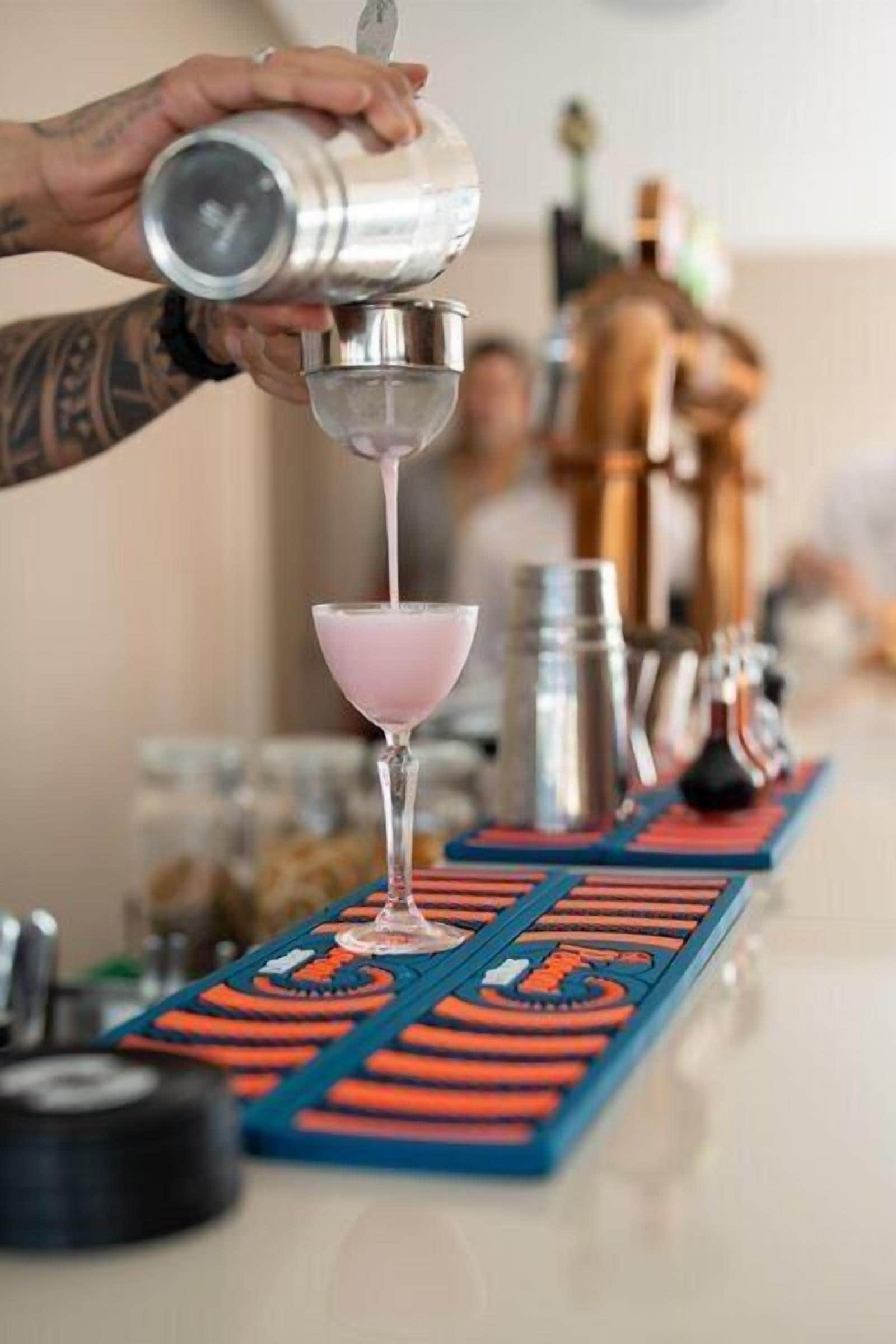 Un cantinero sirviendo una bebida en una copa de martini.