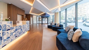 A modern hotel lobby with a reception desk, seating area, and large windows. - Jupiter Porto Hotel - Rooftop & Spa (Porto)