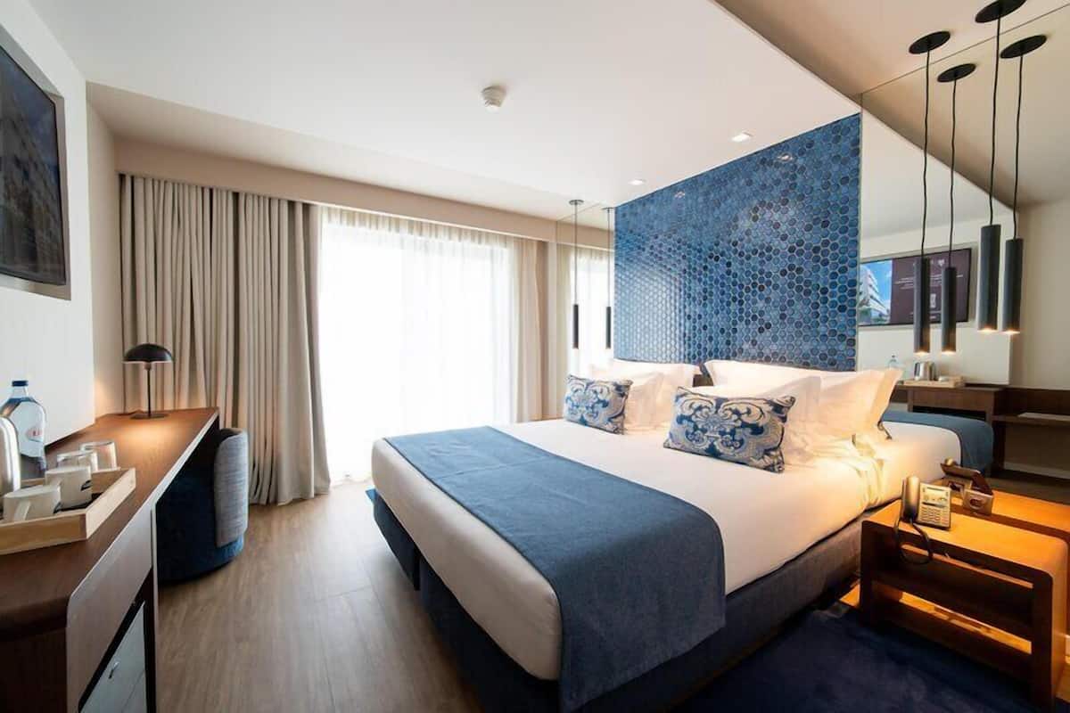 Una habitación de hotel moderna con una cama grande, un escritorio y una zona de estar.