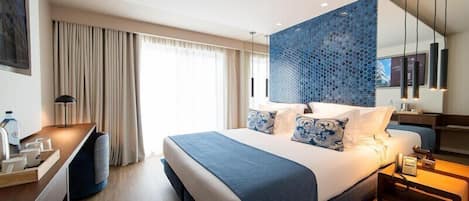 Ett modernt hotellrum med en stor säng, ett skrivbord och en sittgrupp.