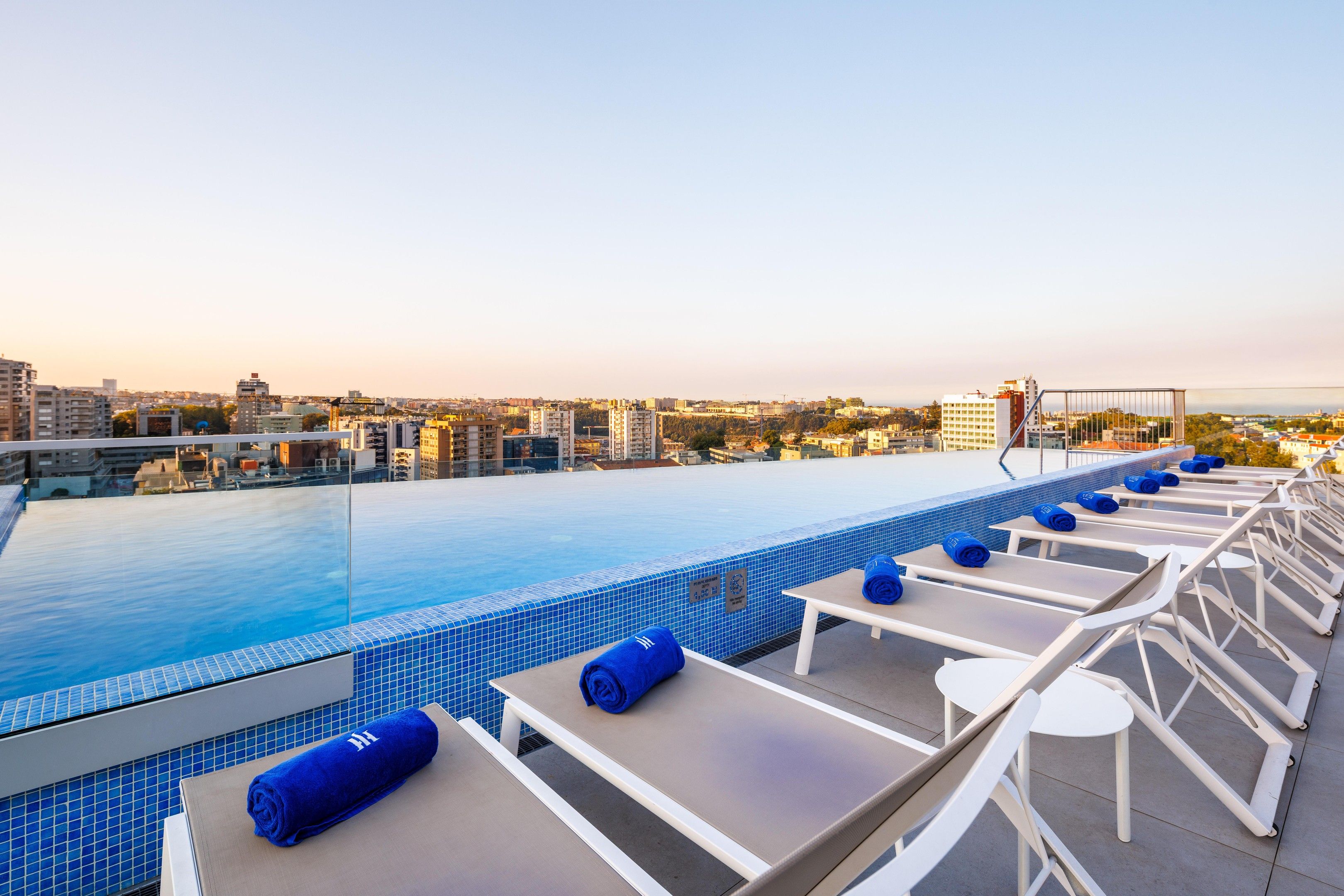 Zona de piscina en la azotea con sillones y vistas a la ciudad.