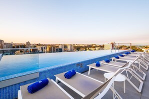 A rooftop pool area with lounge chairs and a view of the cityscape.
