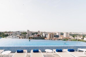 A rooftop infinity pool with lounge chairs and a cityscape view. - Jupiter Porto Hotel - Rooftop & Spa (Porto)
