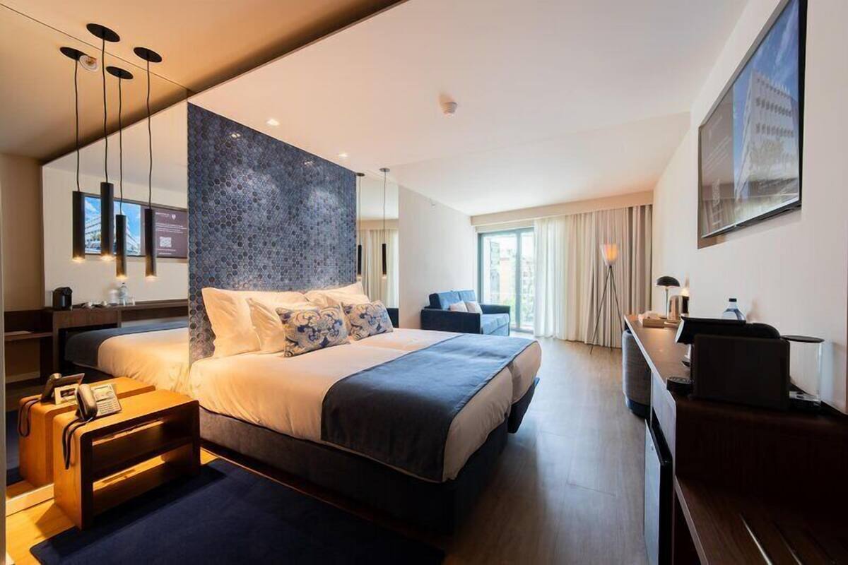 Una habitación de hotel moderna con una cama grande, un escritorio y vistas de la ciudad.